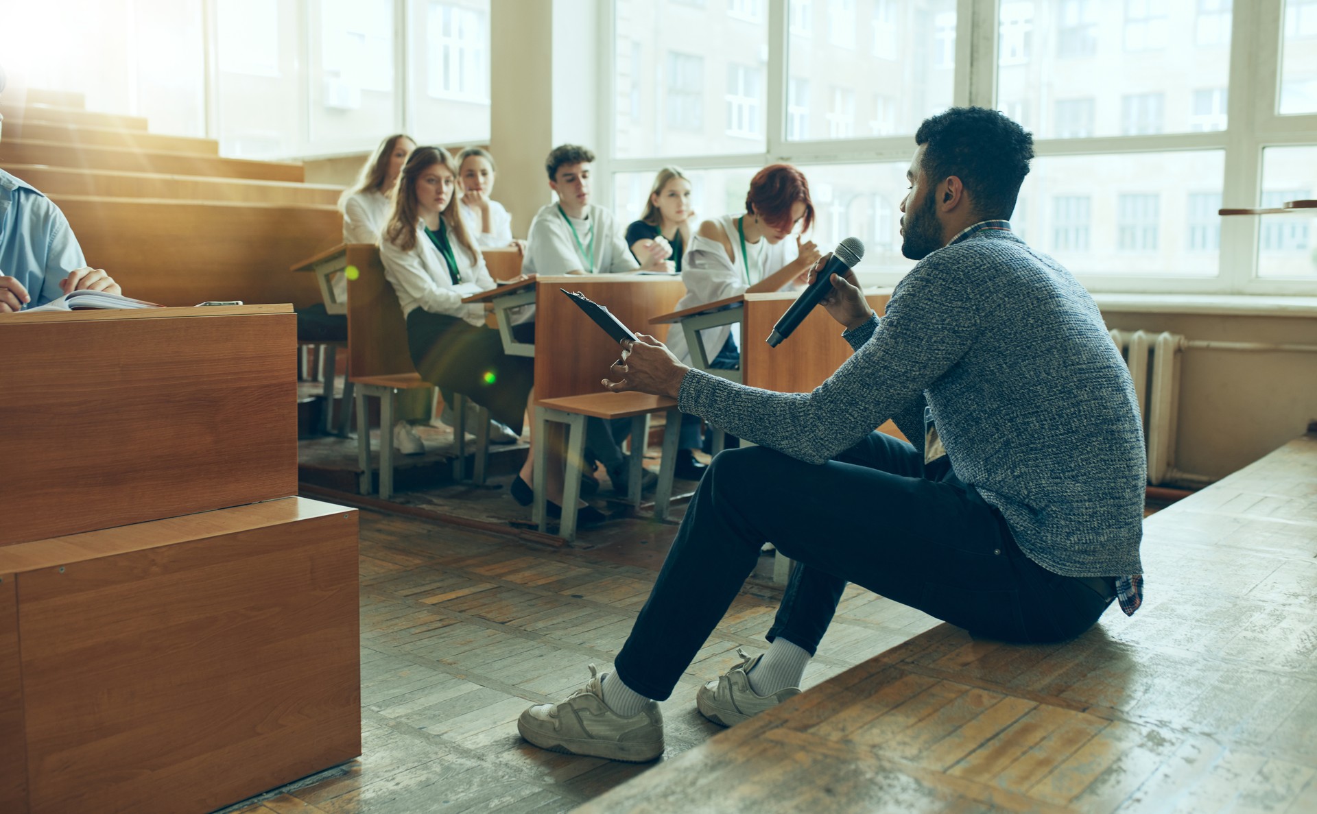 Young man, teacher leaning lecture to group of multiracial people sitting in university classroom. Preparing for exams